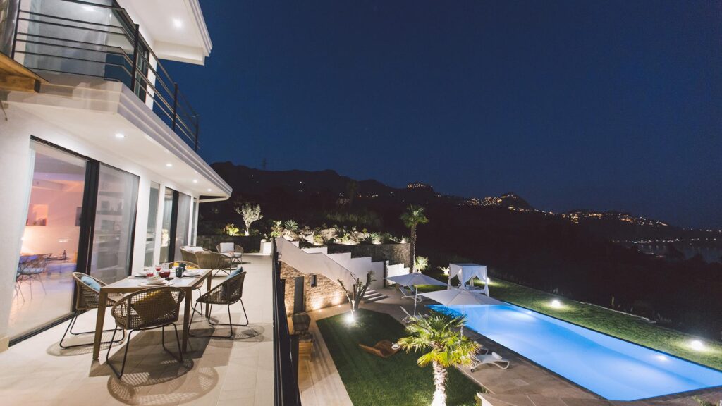 Shot at night of Miranda, there are lit up mountainsides from the village lights and the pool is also lit